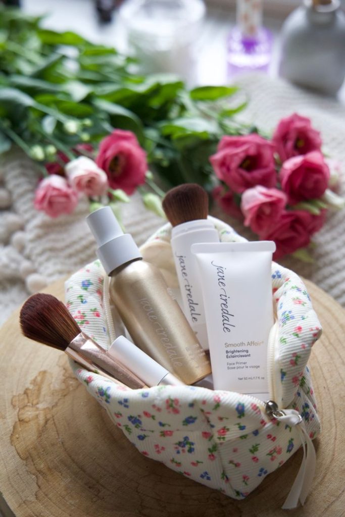 Chic beauty setup featuring a floral bag with skincare products and brushes on a wooden surface. Ideal for beauty and lifestyle themes.